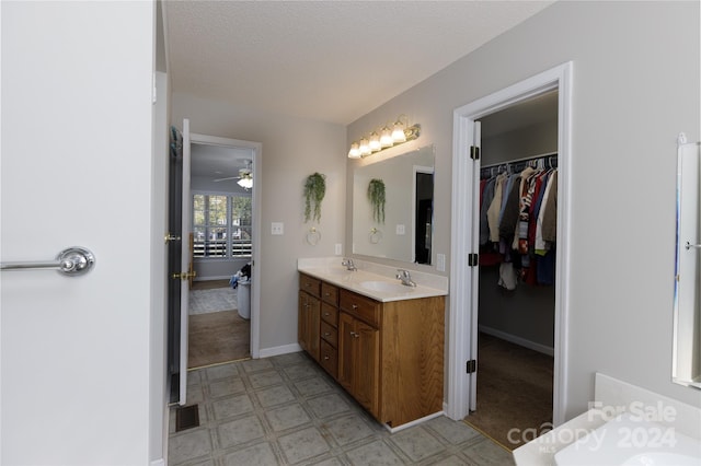 bathroom featuring vanity, ceiling fan, and a textured ceiling