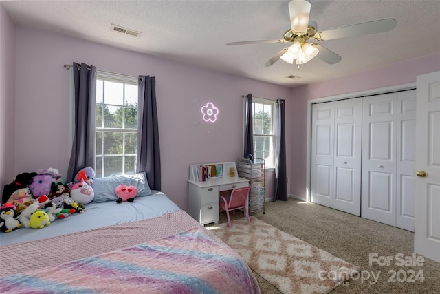 bedroom with light carpet, multiple windows, a textured ceiling, and ceiling fan