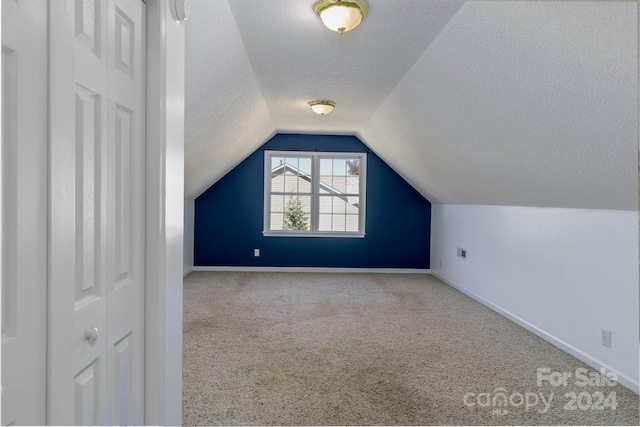 bonus room featuring a textured ceiling, light colored carpet, and vaulted ceiling