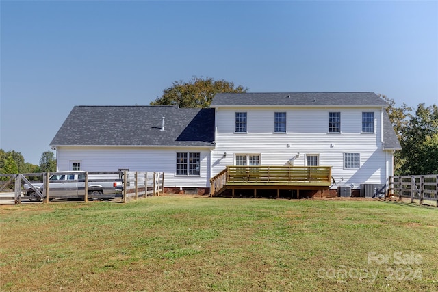 back of property with a wooden deck, cooling unit, and a lawn