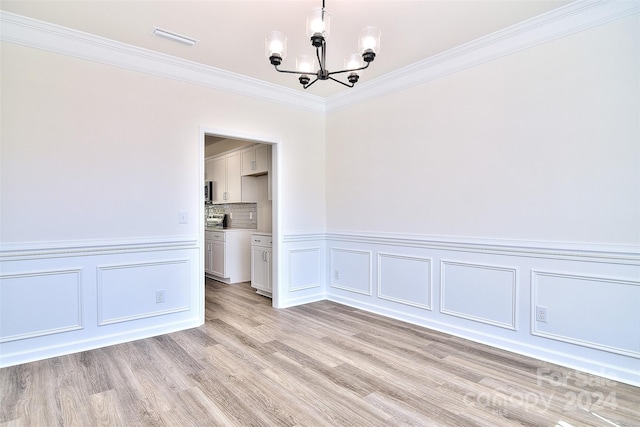 empty room with ornamental molding, a chandelier, and light wood-type flooring