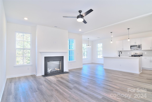 unfurnished living room featuring ceiling fan, a healthy amount of sunlight, and light wood-type flooring