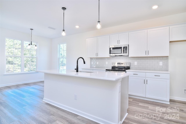 kitchen with appliances with stainless steel finishes, white cabinetry, and an island with sink