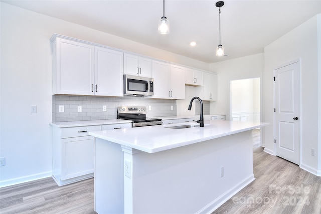 kitchen with white cabinets, stainless steel appliances, and an island with sink