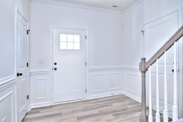 foyer entrance featuring crown molding and light hardwood / wood-style flooring