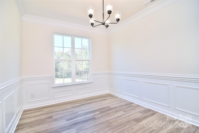 spare room featuring ornamental molding, a notable chandelier, and light wood-type flooring