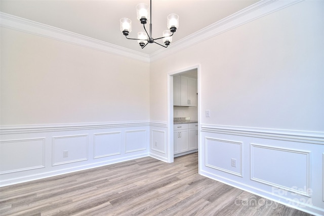 unfurnished dining area with ornamental molding, a chandelier, and light hardwood / wood-style floors