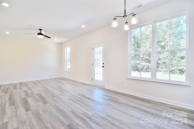 empty room featuring ceiling fan, a healthy amount of sunlight, and light wood-type flooring