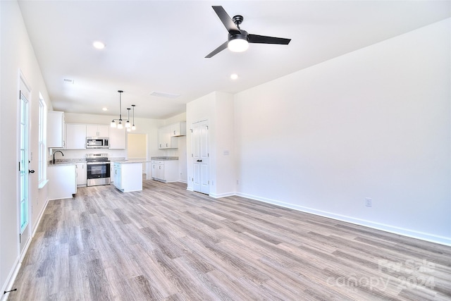 unfurnished living room featuring a wealth of natural light, sink, light wood-type flooring, and ceiling fan