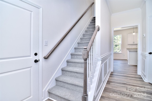 staircase with crown molding and hardwood / wood-style flooring