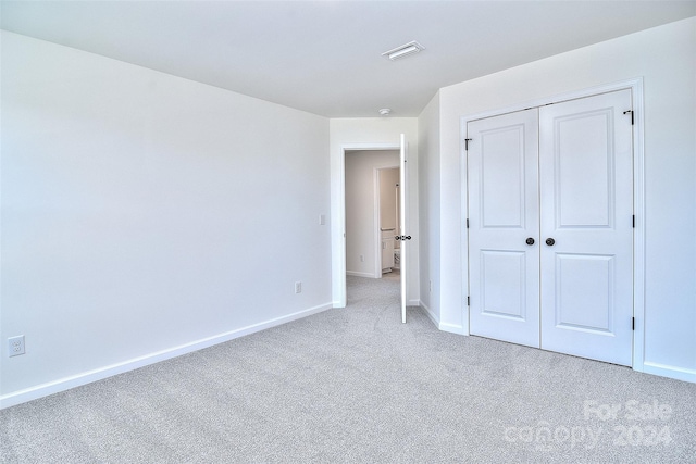 unfurnished bedroom with a closet and light colored carpet