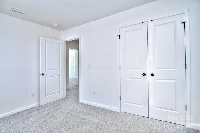 unfurnished bedroom featuring a closet and light colored carpet