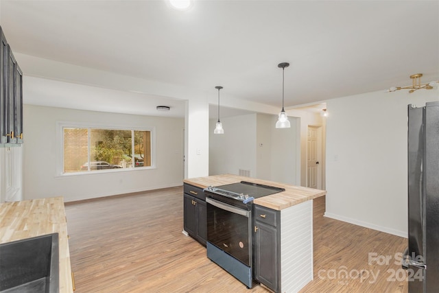 kitchen featuring black / electric stove, butcher block countertops, light hardwood / wood-style flooring, and hanging light fixtures