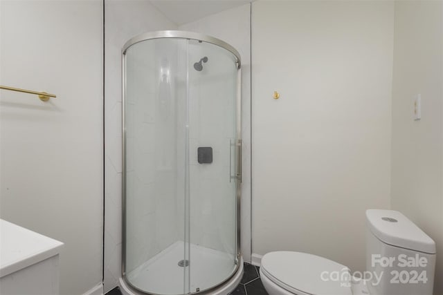 bathroom featuring toilet, a shower with shower door, vanity, and tile patterned floors