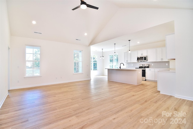 kitchen with white cabinets, stainless steel appliances, light hardwood / wood-style floors, and an island with sink