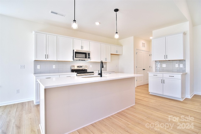 kitchen with a kitchen island with sink, light hardwood / wood-style flooring, white cabinets, appliances with stainless steel finishes, and tasteful backsplash