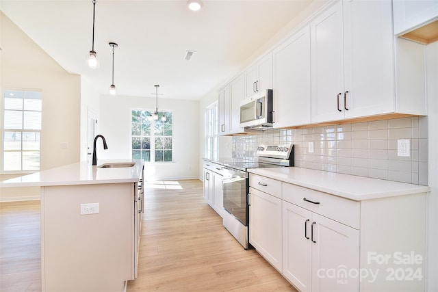 kitchen featuring light hardwood / wood-style flooring, a center island with sink, sink, white cabinets, and appliances with stainless steel finishes