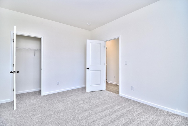 unfurnished bedroom with light carpet and a closet