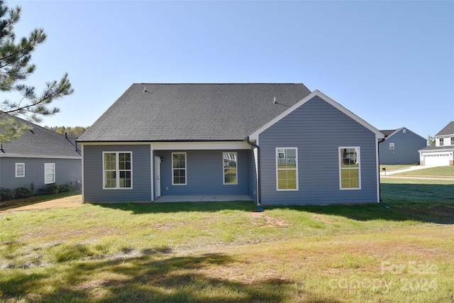 rear view of house with a patio area, a yard, and a garage