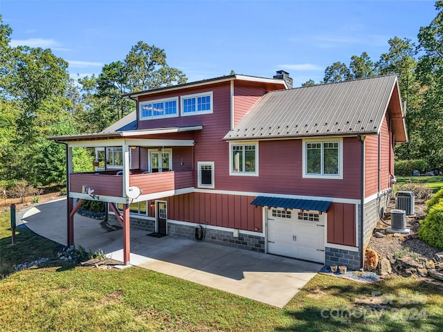 rear view of property featuring a lawn, cooling unit, and a garage