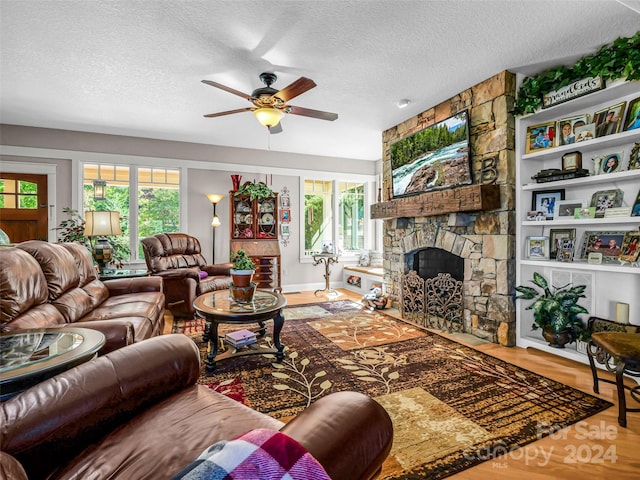 living room featuring ceiling fan, a textured ceiling, a fireplace, and hardwood / wood-style floors