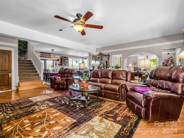 living room with wood-type flooring and ceiling fan with notable chandelier