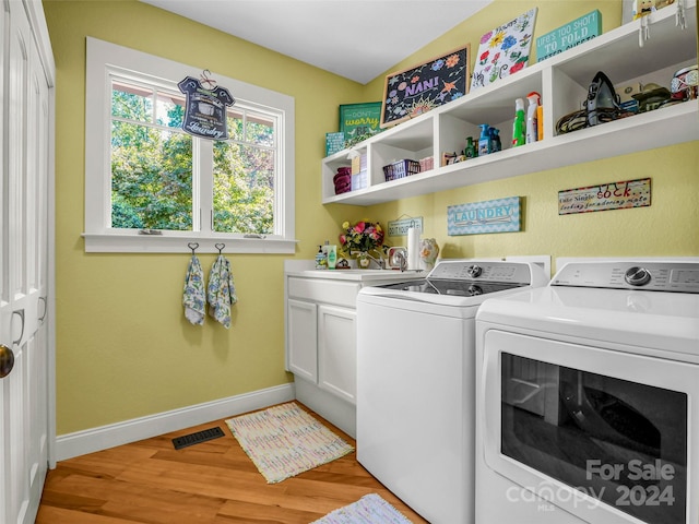 laundry area with sink, light hardwood / wood-style floors, cabinets, and washer and dryer