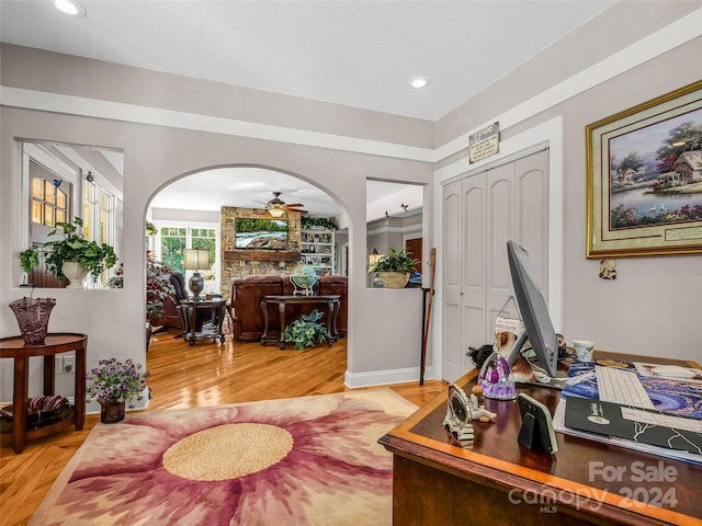 office space featuring ceiling fan, wood-type flooring, and a fireplace