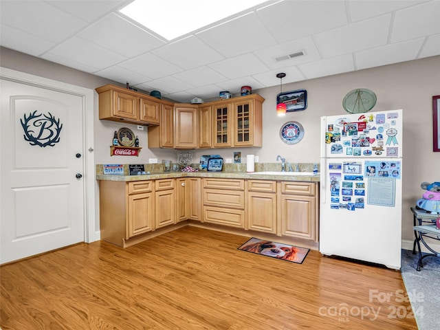 kitchen with white fridge, light hardwood / wood-style flooring, pendant lighting, and sink