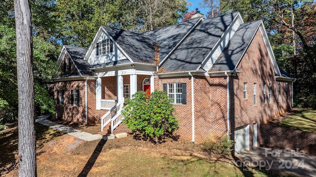 view of front of house featuring roof with shingles, a chimney, and brick siding