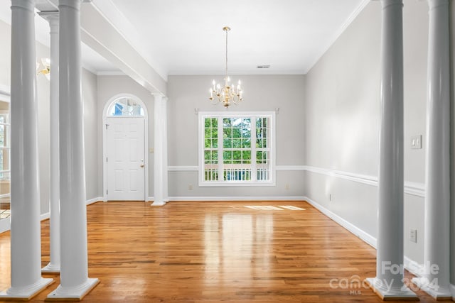 entryway with crown molding, light hardwood / wood-style flooring, and an inviting chandelier