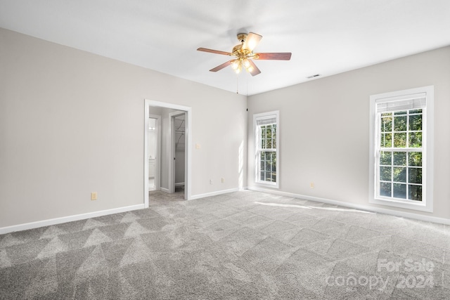 unfurnished room featuring carpet floors, ceiling fan, a healthy amount of sunlight, and visible vents