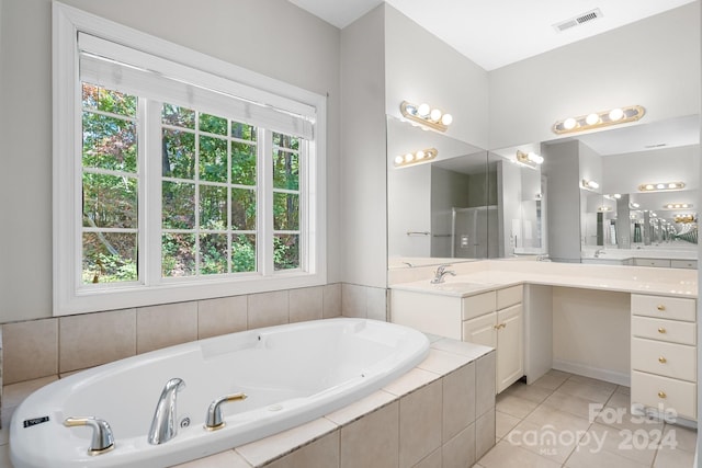 bathroom with vanity, tiled tub, a healthy amount of sunlight, and tile patterned flooring