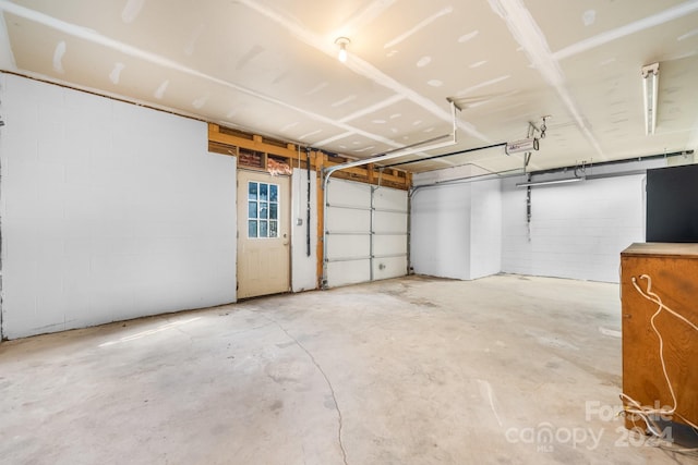 garage with a garage door opener and concrete block wall