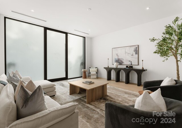 living room with a wall of windows and light wood-type flooring