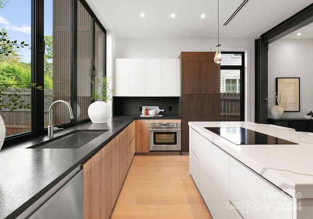 kitchen featuring appliances with stainless steel finishes, sink, white cabinetry, and pendant lighting