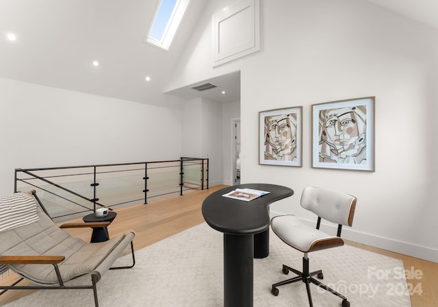 office area featuring high vaulted ceiling, light hardwood / wood-style floors, and a skylight