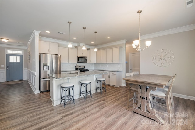 kitchen featuring white cabinets, appliances with stainless steel finishes, an island with sink, and light hardwood / wood-style flooring