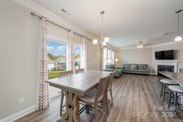 dining area with ornamental molding, hardwood / wood-style floors, and ceiling fan with notable chandelier