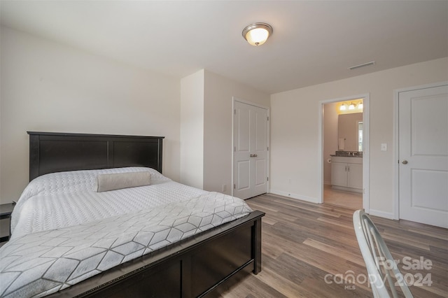 bedroom featuring connected bathroom and light hardwood / wood-style flooring