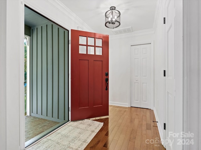 entrance foyer featuring light hardwood / wood-style floors, crown molding, and a chandelier