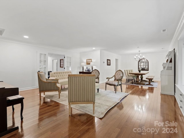 living room with crown molding, a notable chandelier, and light hardwood / wood-style floors