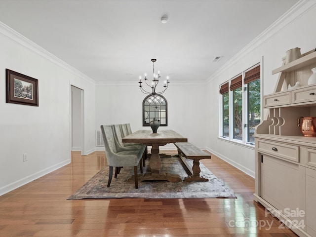 dining space with crown molding, a notable chandelier, and light wood-type flooring