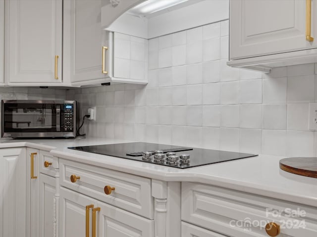 kitchen featuring black electric cooktop, white cabinetry, and backsplash