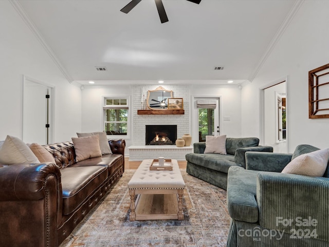 living room with crown molding, a healthy amount of sunlight, wood-type flooring, and a brick fireplace