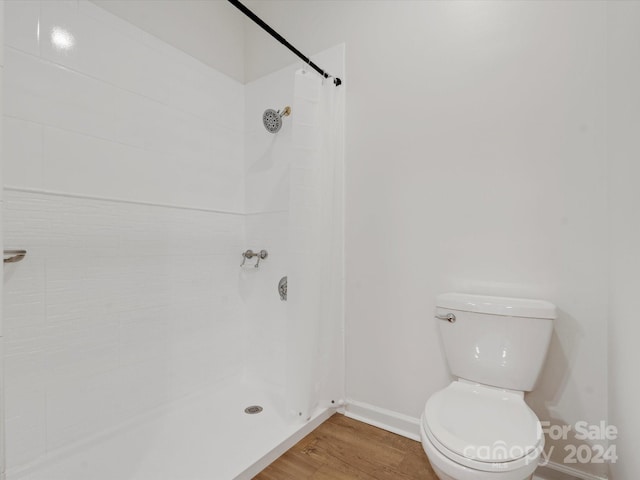 bathroom with toilet, hardwood / wood-style flooring, and tiled shower