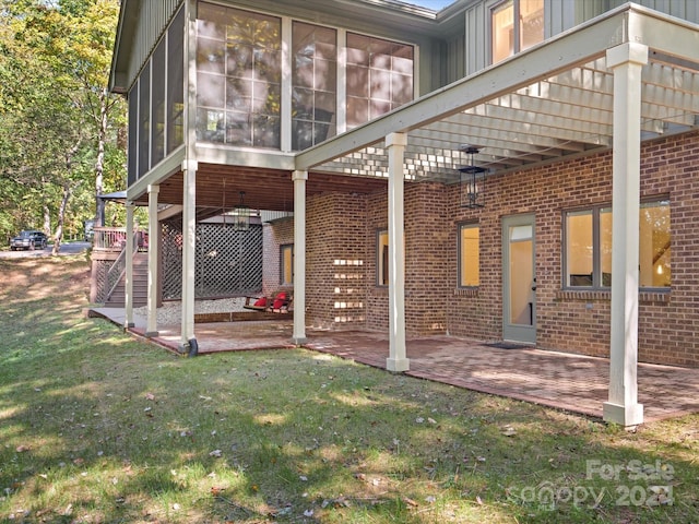 back of house with a sunroom, a patio area, and a lawn