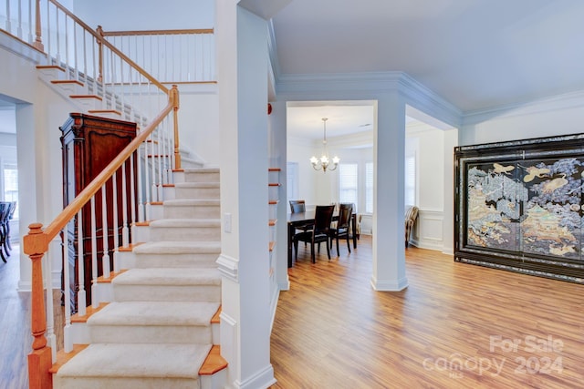 stairway with a notable chandelier, crown molding, and hardwood / wood-style flooring