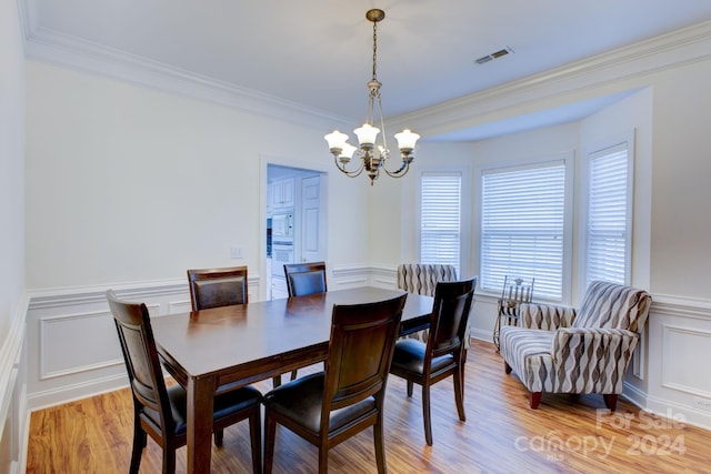 dining space featuring crown molding, a notable chandelier, and light hardwood / wood-style flooring