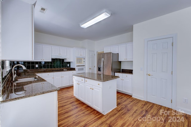 kitchen with sink, a center island, stainless steel refrigerator with ice dispenser, and white cabinets